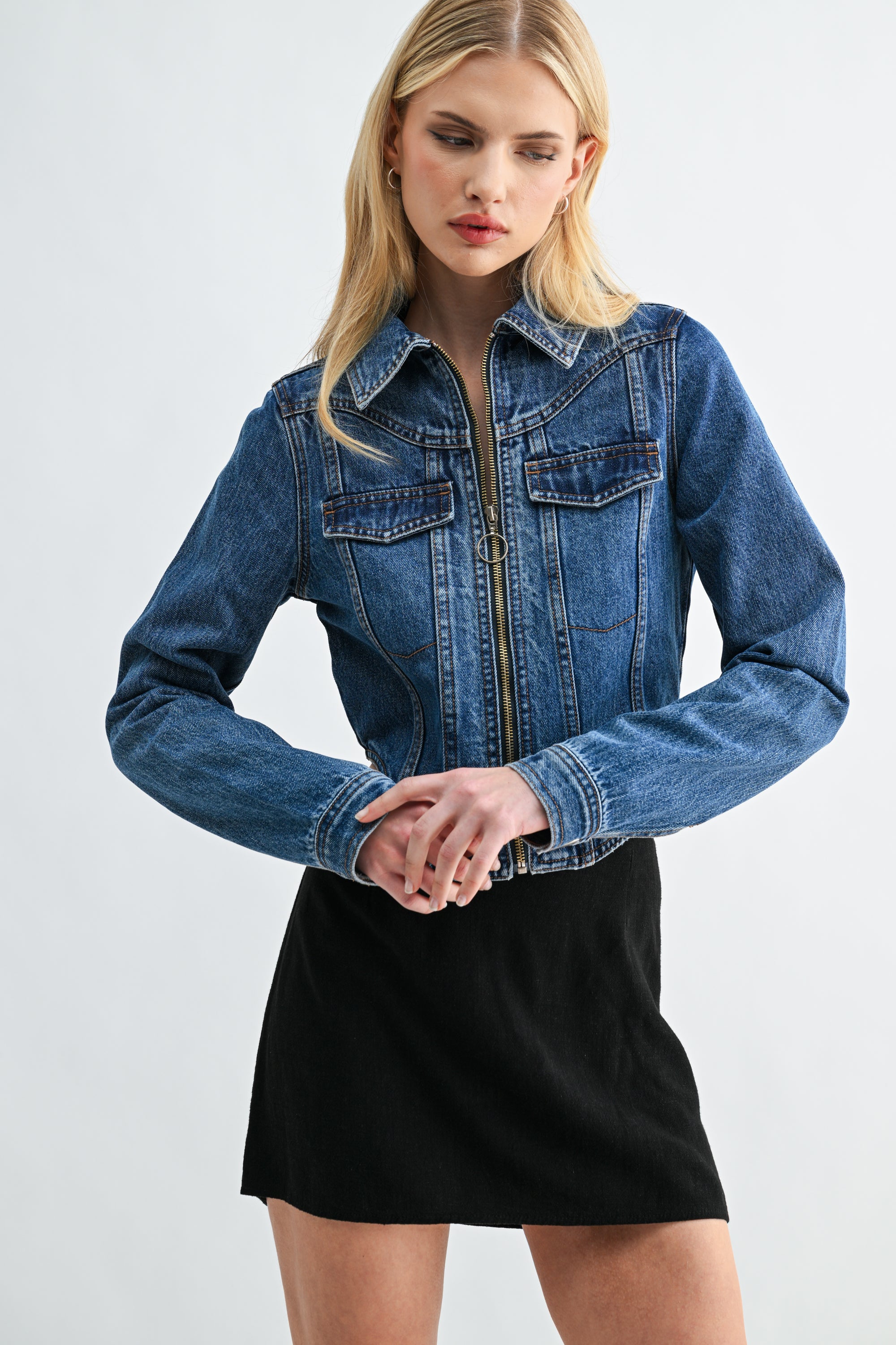 Close-up of front zipper closure and cropped hem on dark wash denim jacket